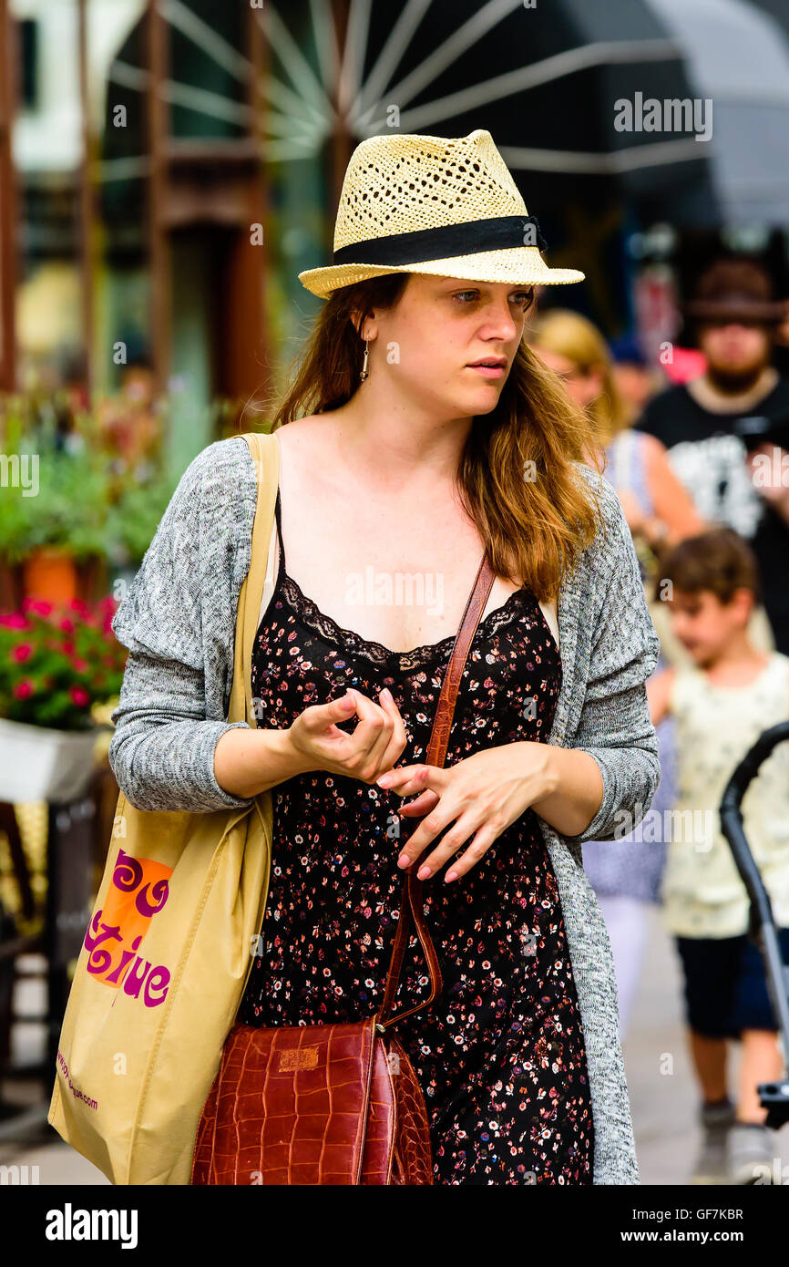 Goteborg, Sweden - July 25, 2016: Unknown young adult woman wearing a straw hat walking down a street with people in the backgro Stock Photo