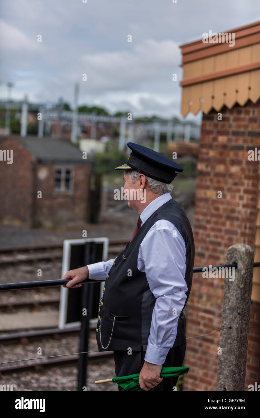 Train guard looks out at the station towards the railway track at the