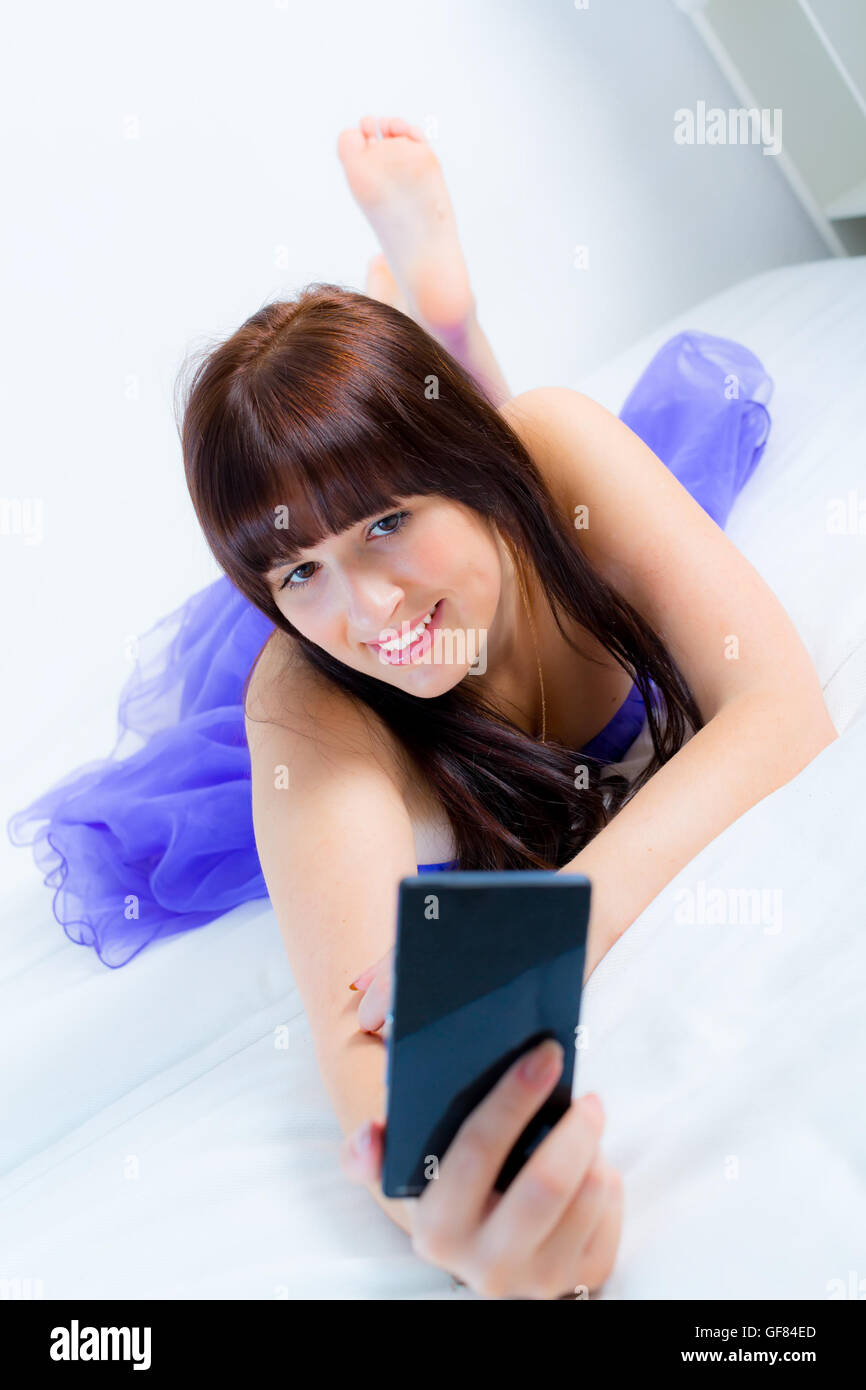 A young girl in a blue evening dress poses for the camera cell phone self-portrait with emotions Stock Photo
