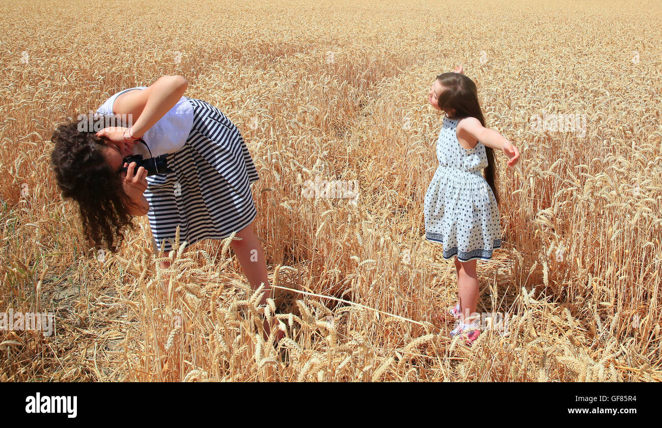 Happy family moments - Young girls having fun ln the wheat field Stock Photo