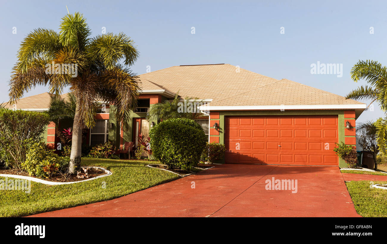 Typical Southwest Florida concrete block and stucco home in the countryside with palm trees, tropical plants and flowers, grass Stock Photo