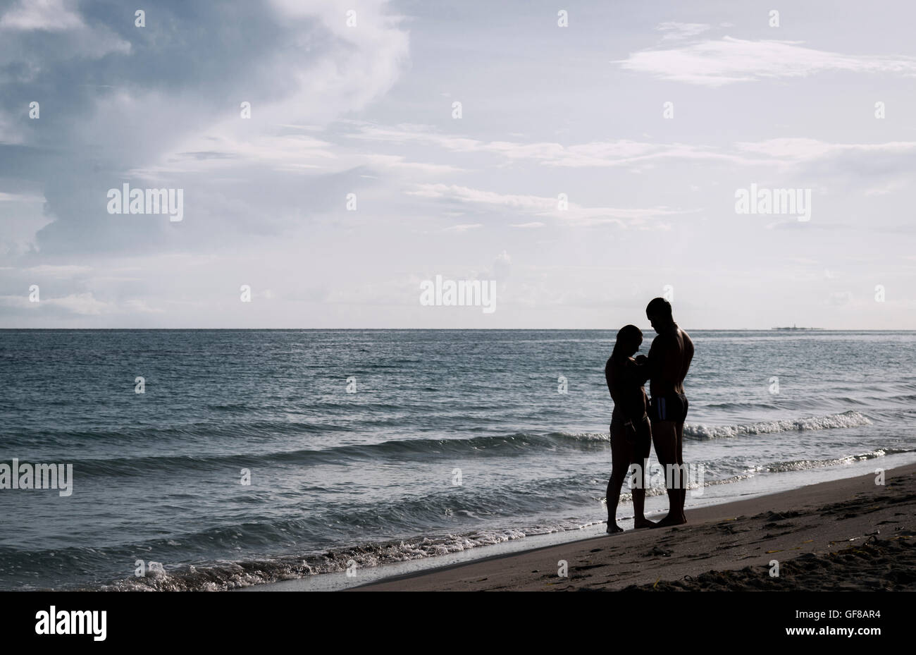 silhouette of a couple on the beach with the sea and sky as background ...