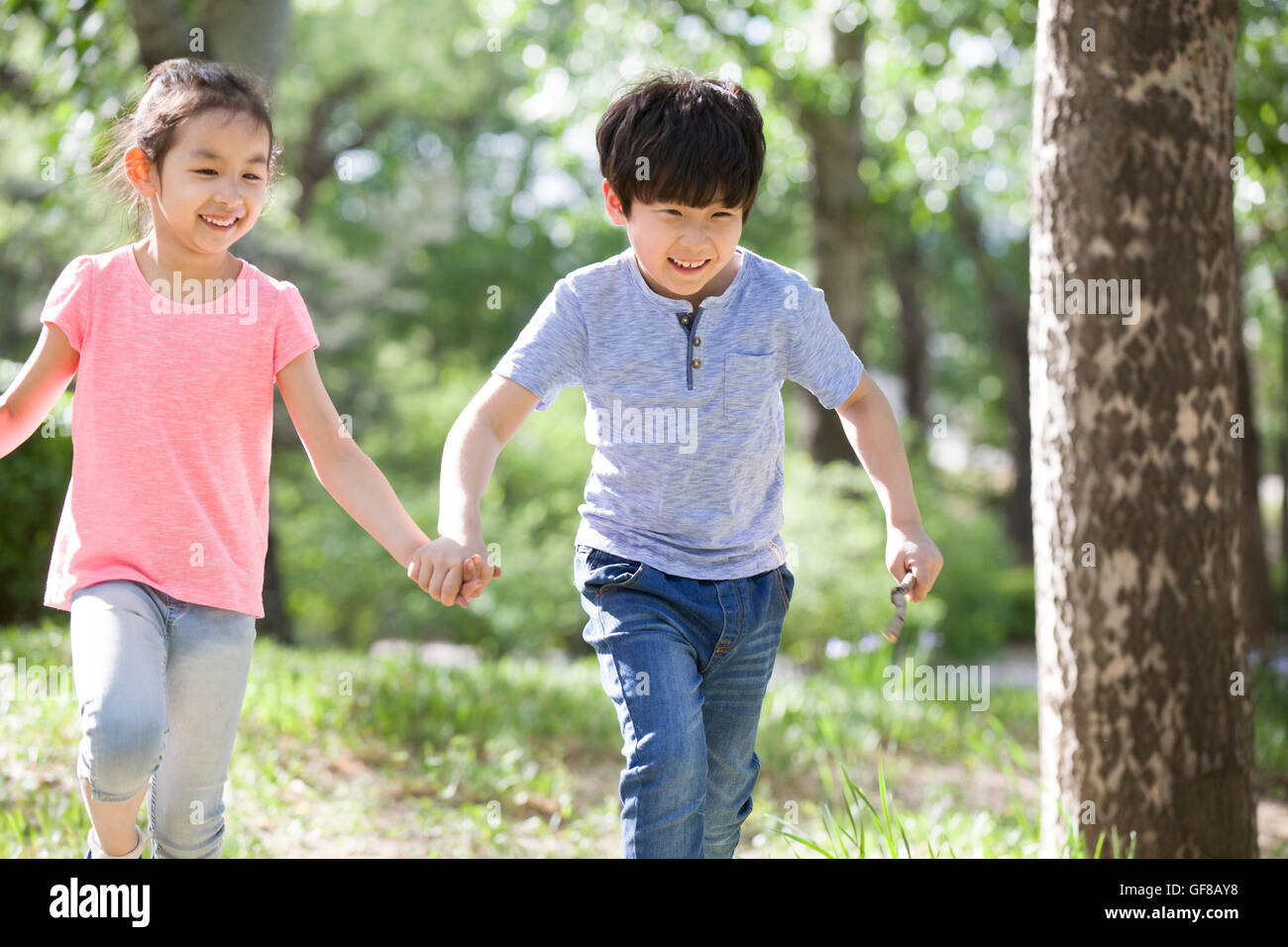 Happy Chinese children holding hands running in woods Stock Photo - Alamy