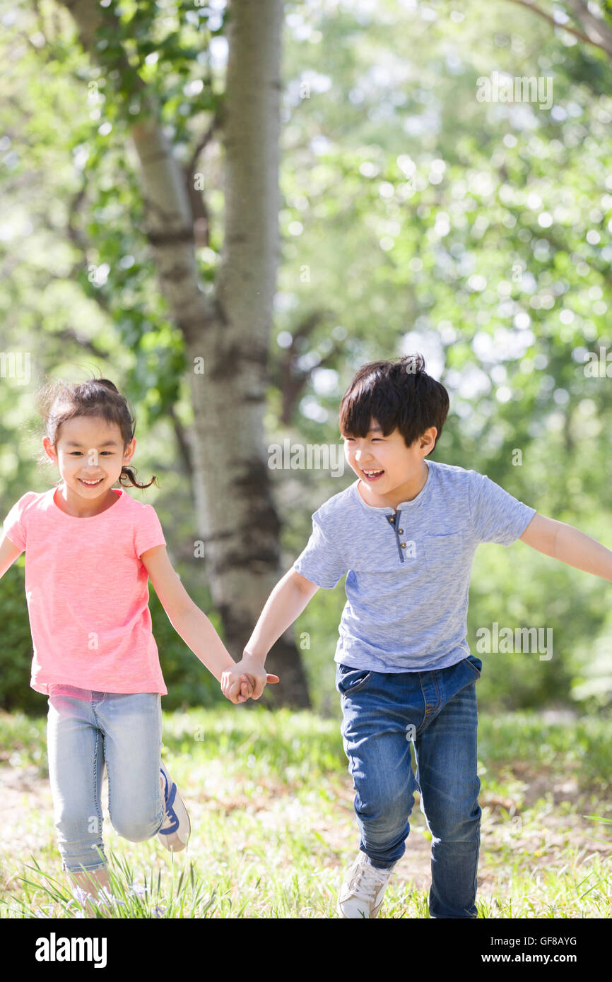 Happy Chinese children holding hands running in woods Stock Photo - Alamy