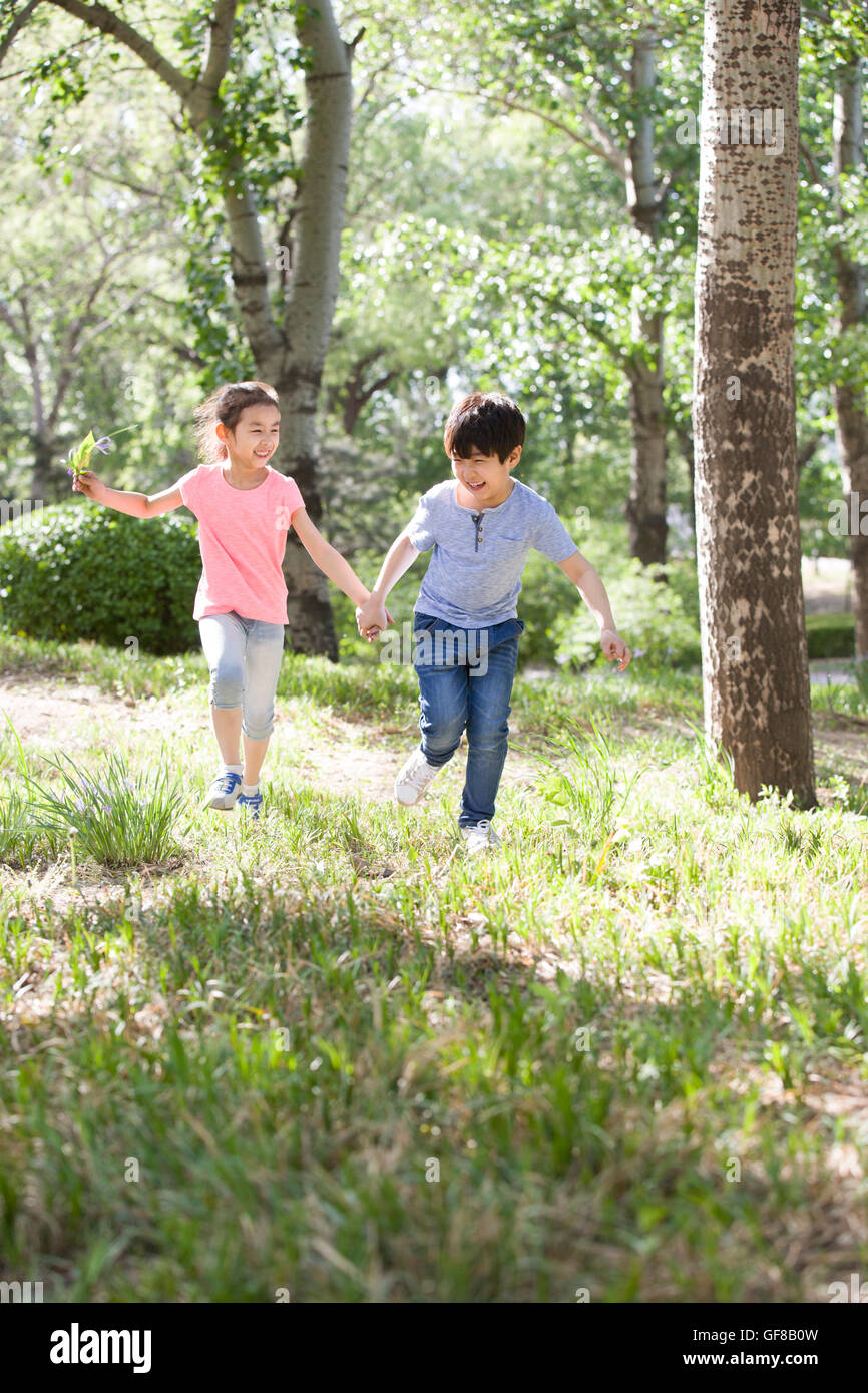 Happy Chinese children holding hands running in woods Stock Photo - Alamy