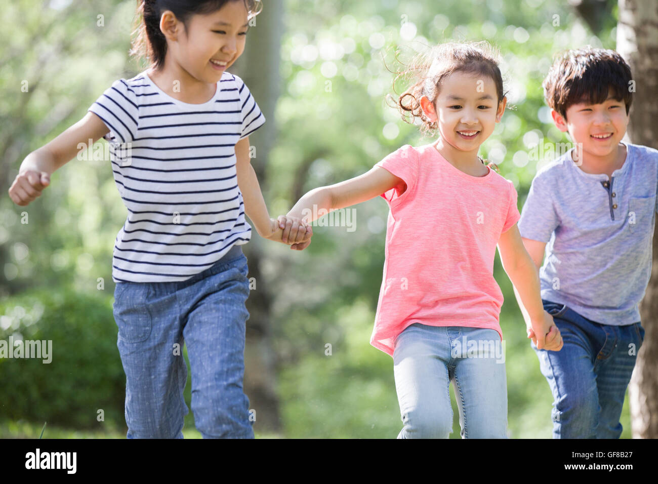 Happy Chinese children holding hands running in woods Stock Photo - Alamy