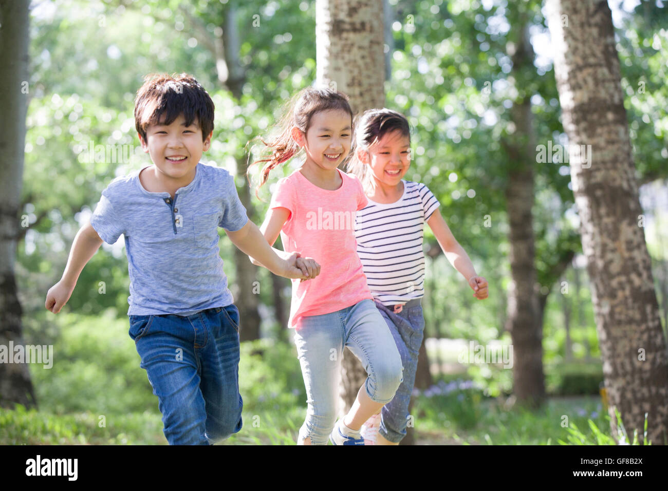 Happy Chinese children holding hands running in woods Stock Photo - Alamy