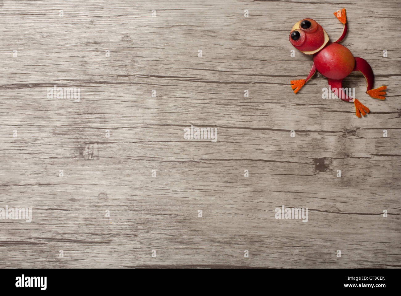 Jumping frog made of apple on wooden background Stock Photo