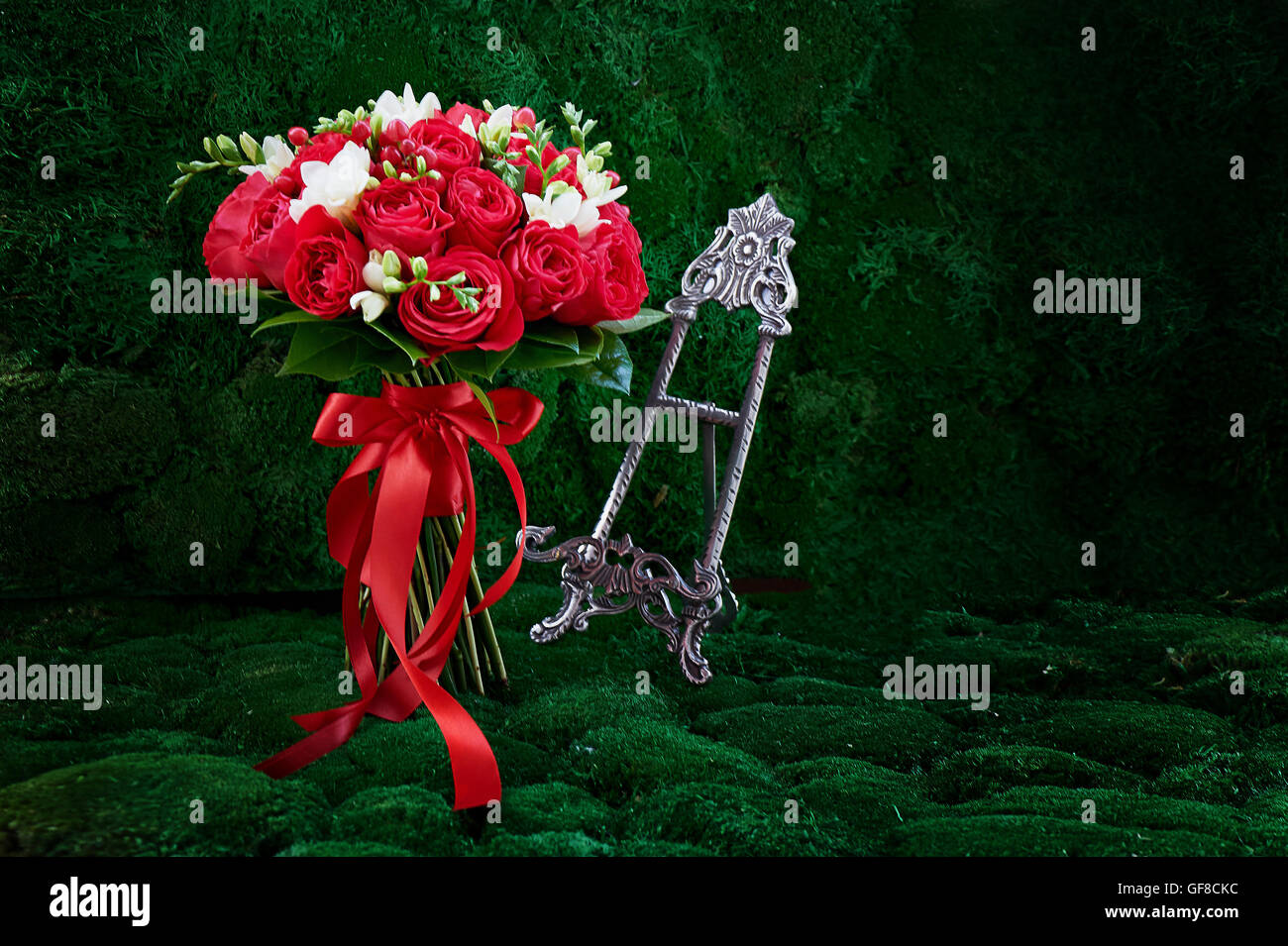dense red bouquet of roses and berries, with red ribbon tied with a bow Stock Photo