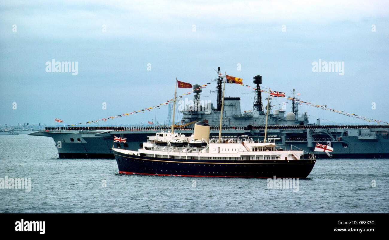 AJAX NEWS PHOTOS. 1977. SPITHEAD, ENGLAND. - ROYAL YACHT - THE ROYAL YACHT BRITANNIA WITH H.M.QUEEN ELIZABETH II EMBARKED, SAILS PAST THE AIRCRAFT CARRIER HMS ARK ROYAL DURING THE 1977 SILVER JUBILEE FLEET REVIEW.   PHOTO:JONATHAN EASTLAND/AJAX  REF:907450 Stock Photo