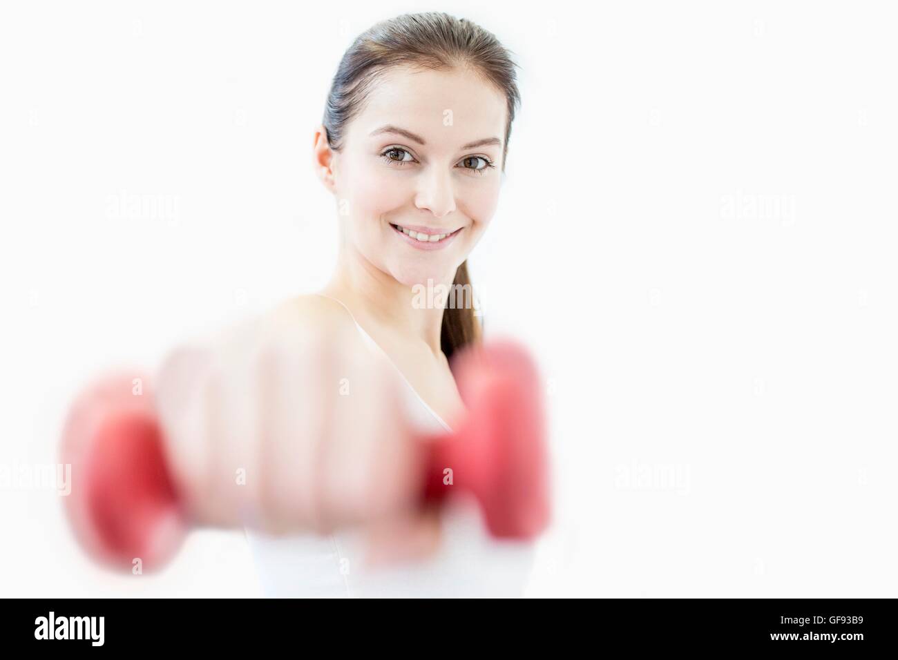 PROPERTY RELEASED. MODEL RELEASED. Smiling young woman working out with dumbbell in gym, portrait. Stock Photo
