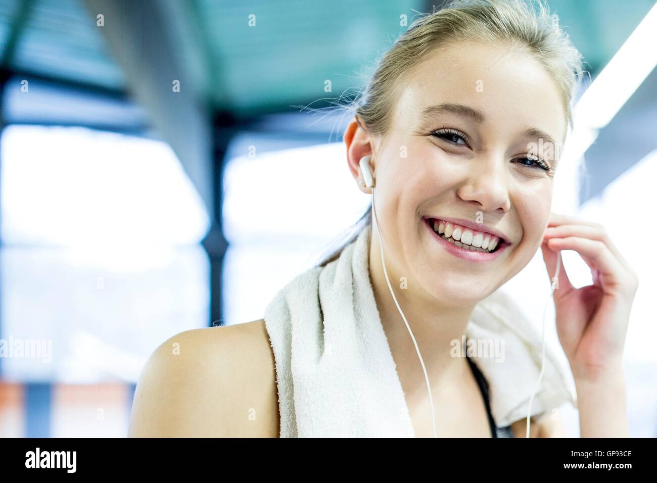 PROPERTY RELEASED. MODEL RELEASED. Young woman wearing arm band adjusting headphones in gym, portrait. Stock Photo