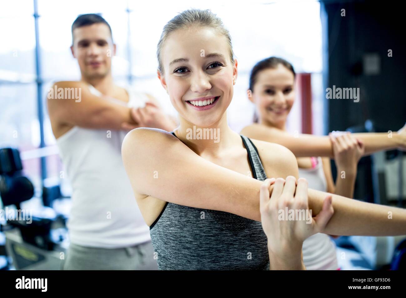 PROPERTY RELEASED. MODEL RELEASED. Young man and women doing warm up exercise in gym. Stock Photo