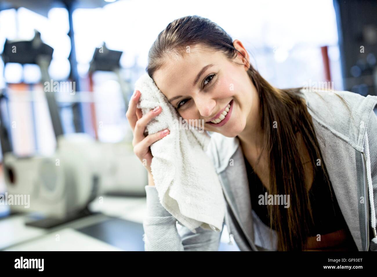 PROPERTY RELEASED. MODEL RELEASED. Portrait young woman wiping her sweat after workout in gym. Stock Photo