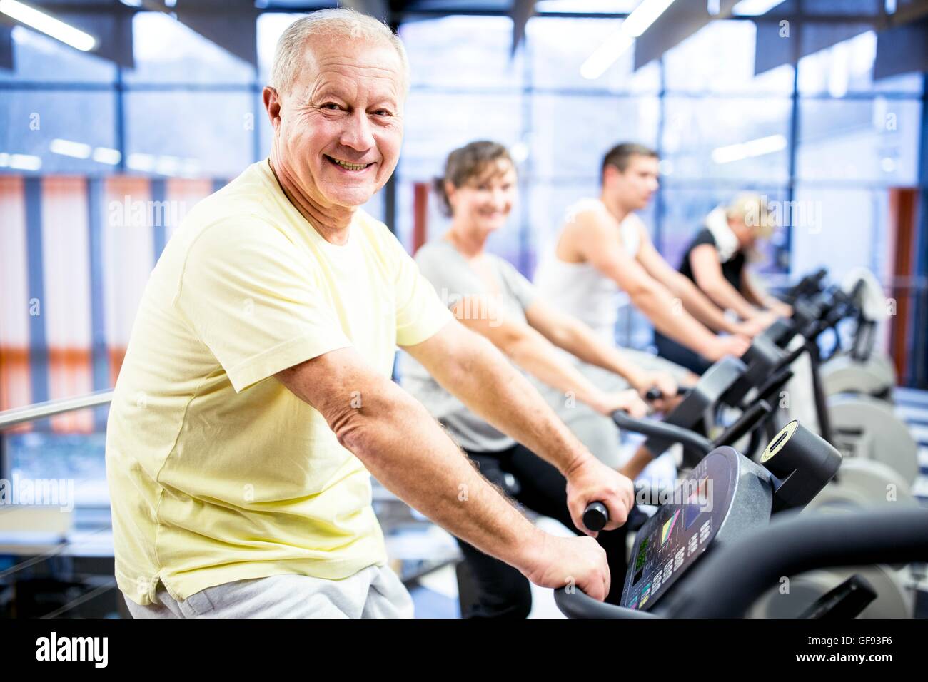 PROPERTY RELEASED. MODEL RELEASED. Portrait senior man exercising on stationary bicycle in gym. Stock Photo