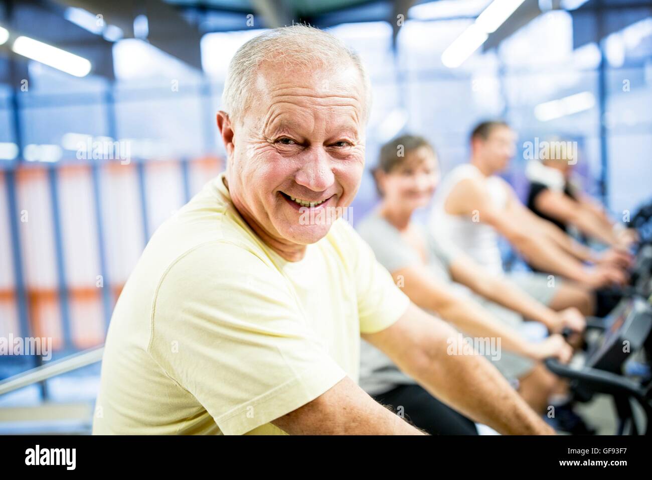 PROPERTY RELEASED. MODEL RELEASED. Portrait senior man exercising on stationary bicycle in gym. Stock Photo