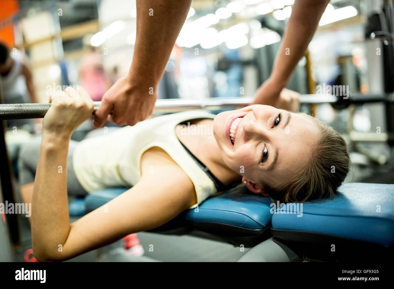 PROPERTY RELEASED. MODEL RELEASED. Young woman using exercising machine and smiling in gym. Stock Photo