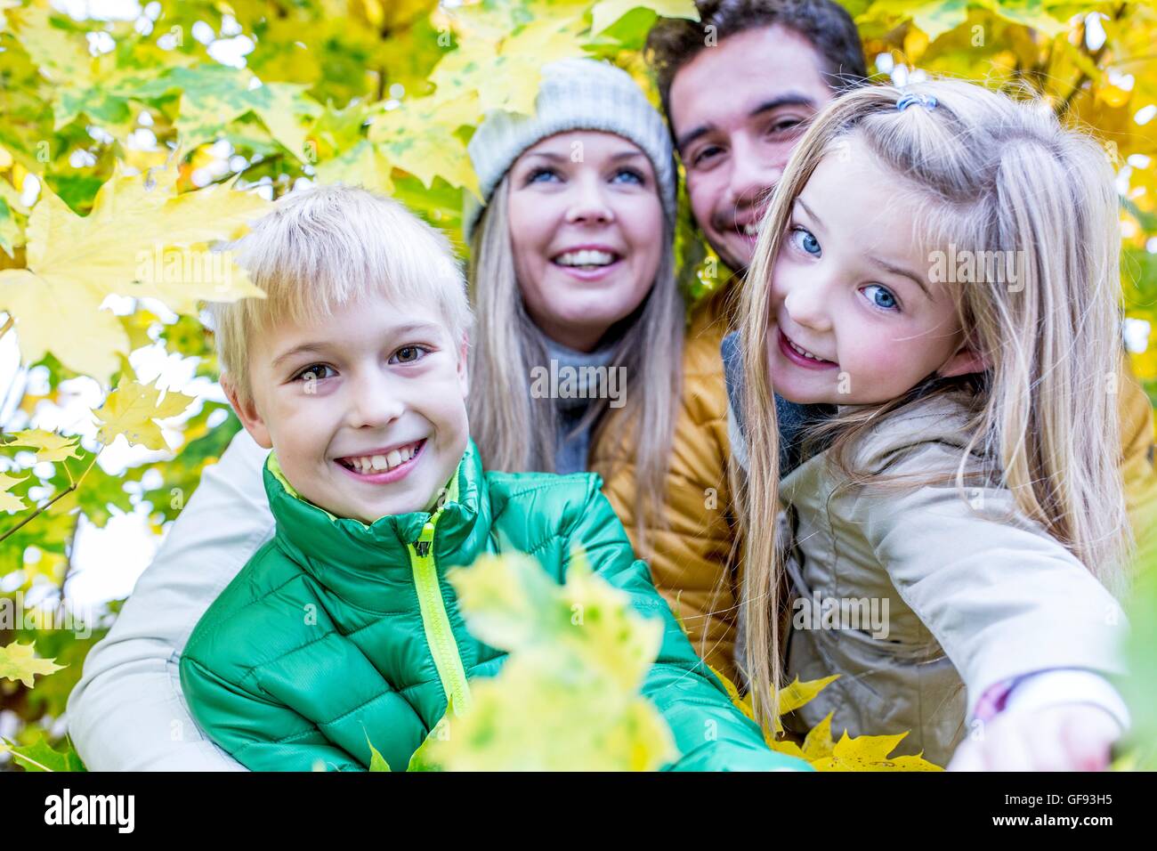 MODEL RELEASED. Family smiling together while surrounded by autumn leaves. Stock Photo