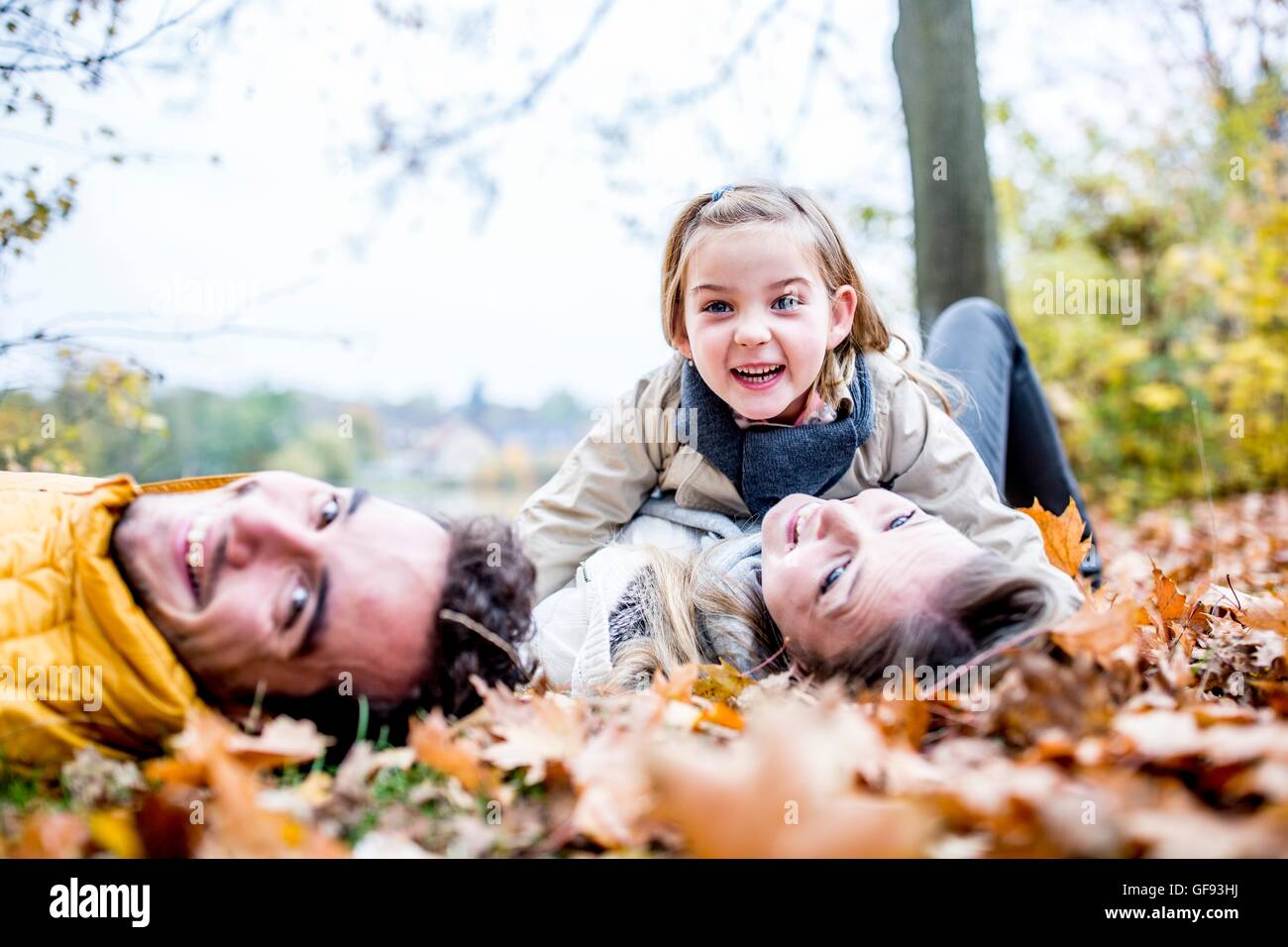 MODEL RELEASED. Family lying on dried leaves in autumn. Stock Photo
