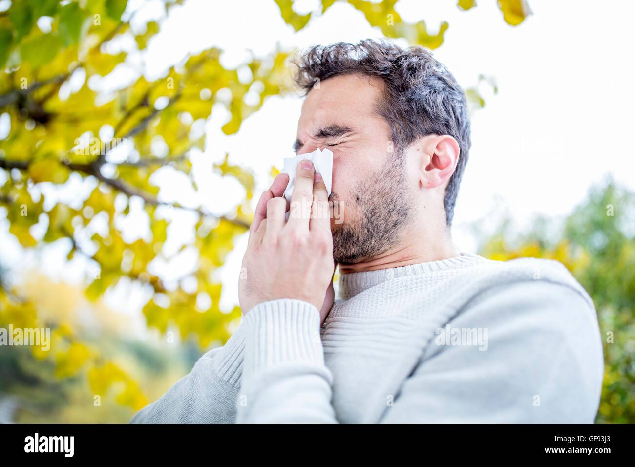 MODEL RELEASED. Young man sneezing, close-up. Stock Photo