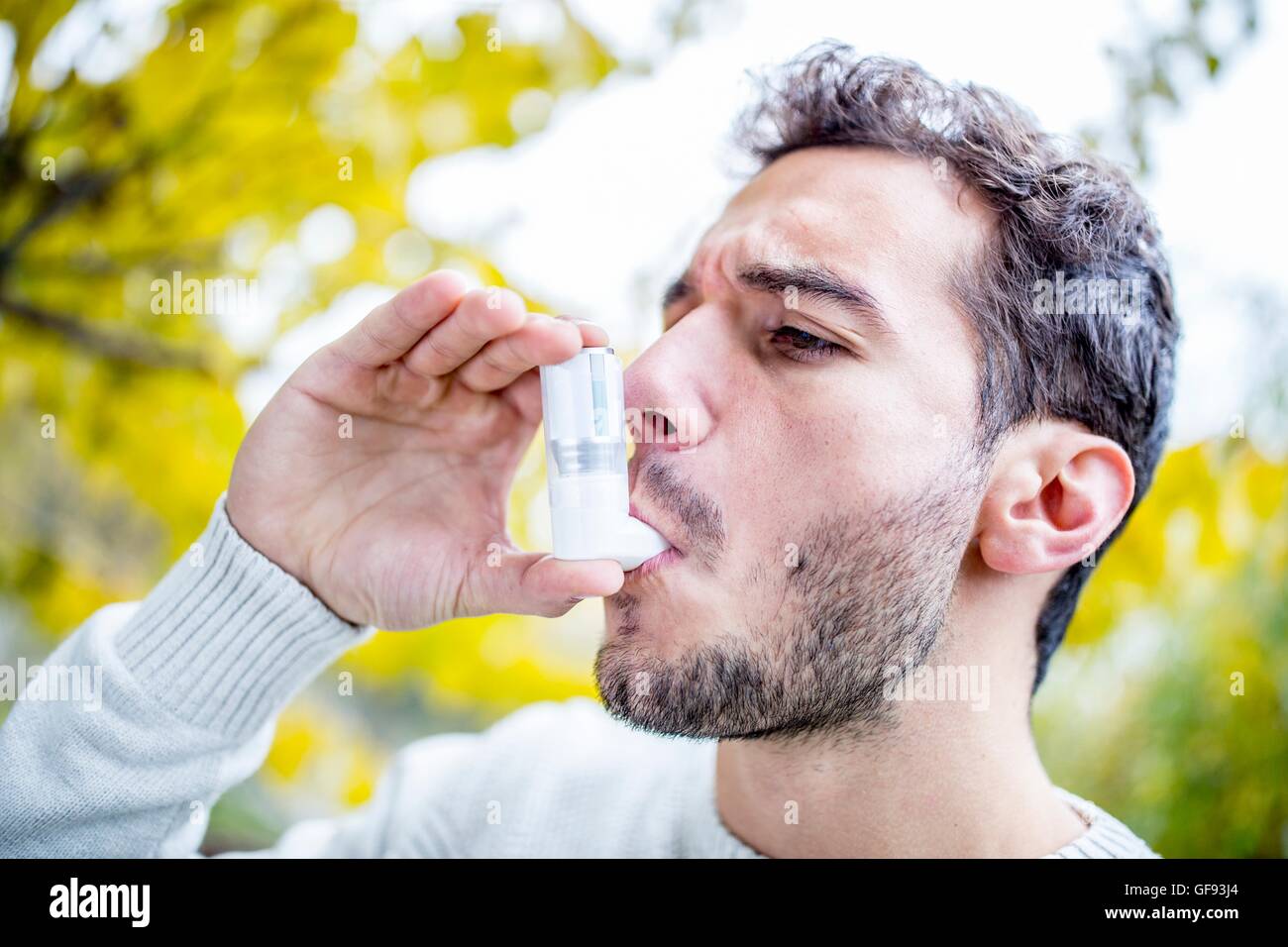 MODEL RELEASED. Young man using asthma inhaler, close-up. Stock Photo