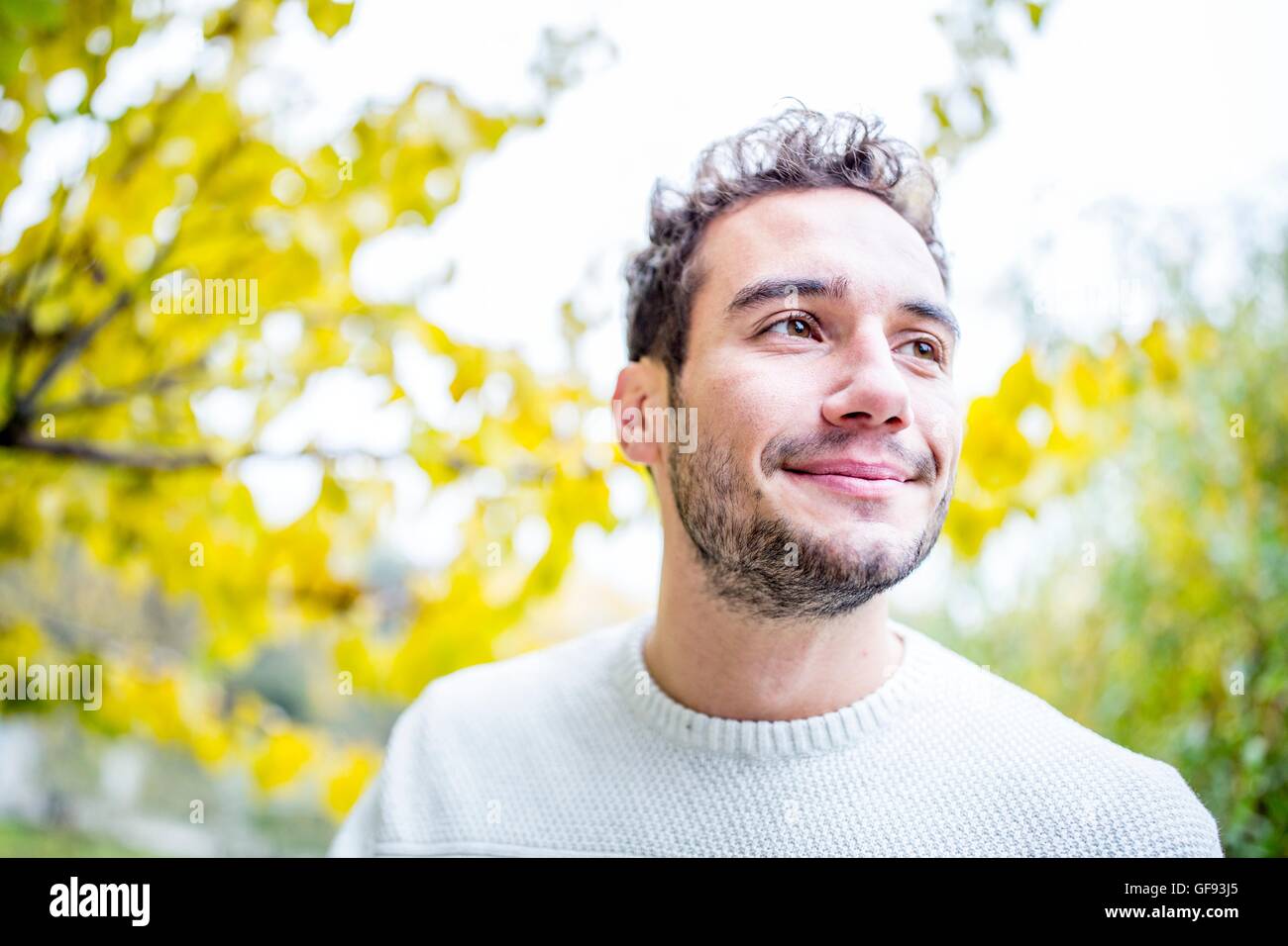 MODEL RELEASED. Young man looking away and smiling, close-up. Stock Photo