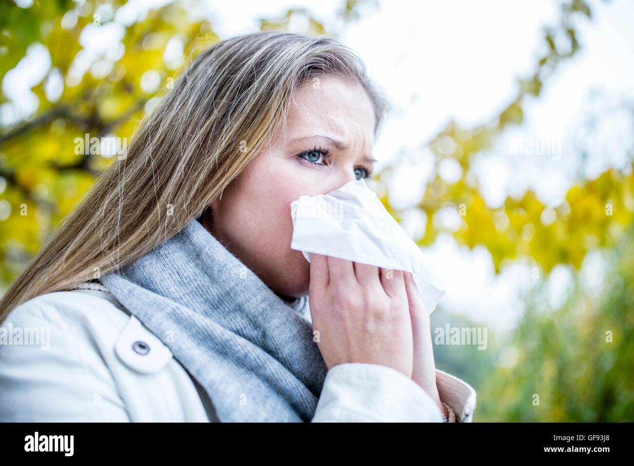 MODEL RELEASED. Young woman sneezing, close-up. Stock Photo
