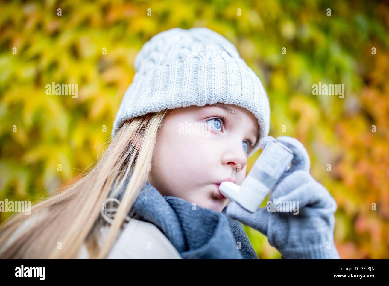 MODEL RELEASED. Young girl using asthma inhaler, close-up. Stock Photo