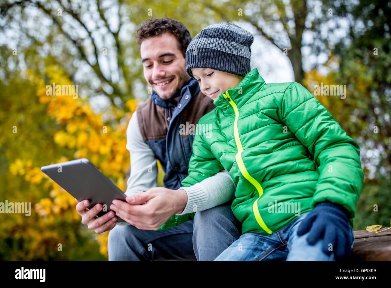MODEL RELEASED. Father and son using digital tablet in autumn. Stock Photo