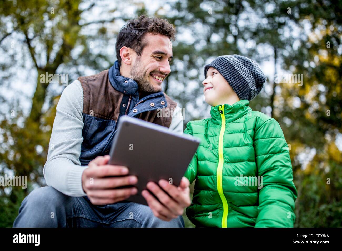 MODEL RELEASED. Father and son using digital tablet in autumn. Stock Photo