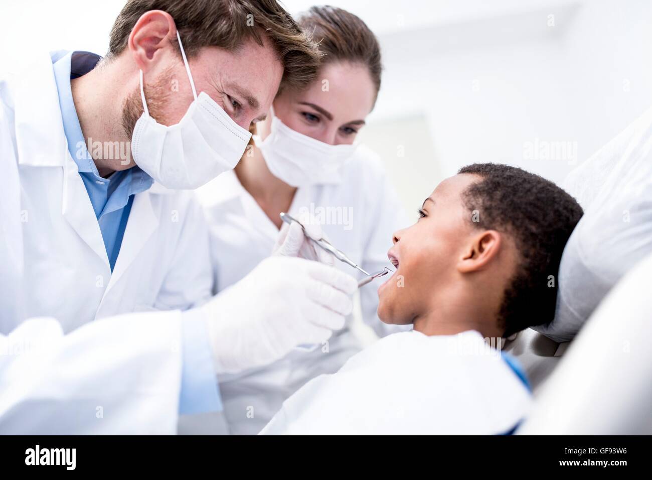 MODEL RELEASED. Doctors examining boy's teeth in clinic, smiling. Stock Photo