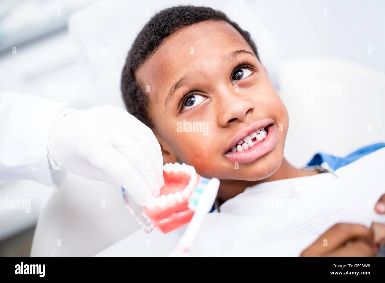 MODEL RELEASED. Dentist showing boy how to brush his teeth. Stock Photo