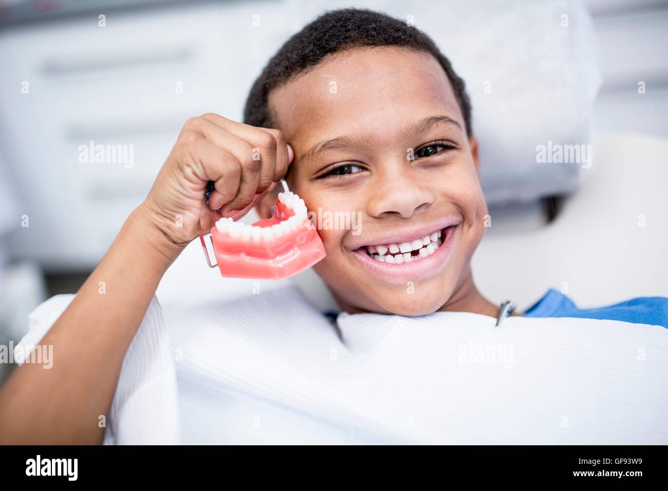 MODEL RELEASED. Portrait of boy holding dentures, smiling. Stock Photo