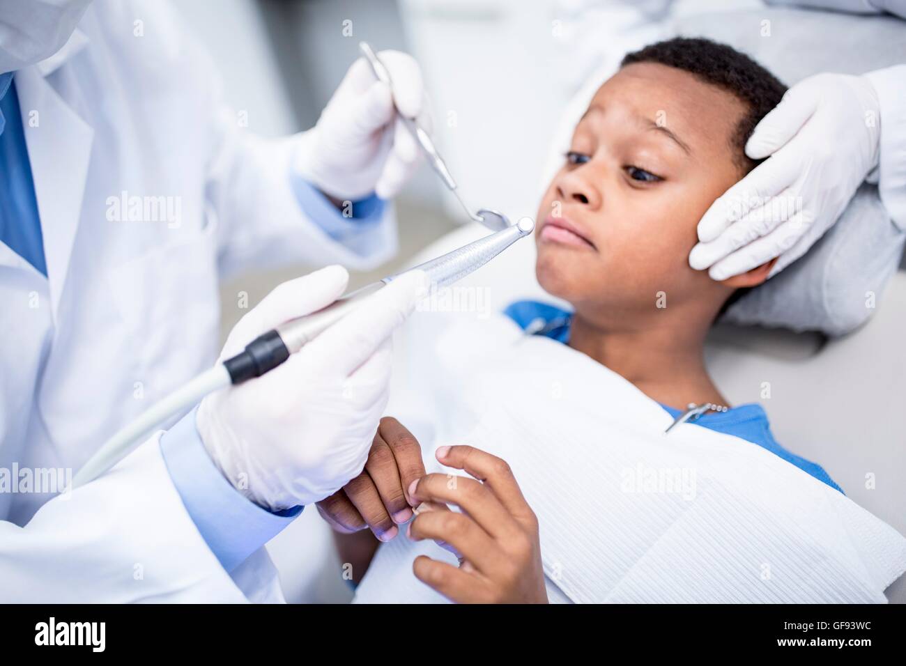 MODEL RELEASED. Scared boy looking at dental drill in dentist's hand. Stock Photo