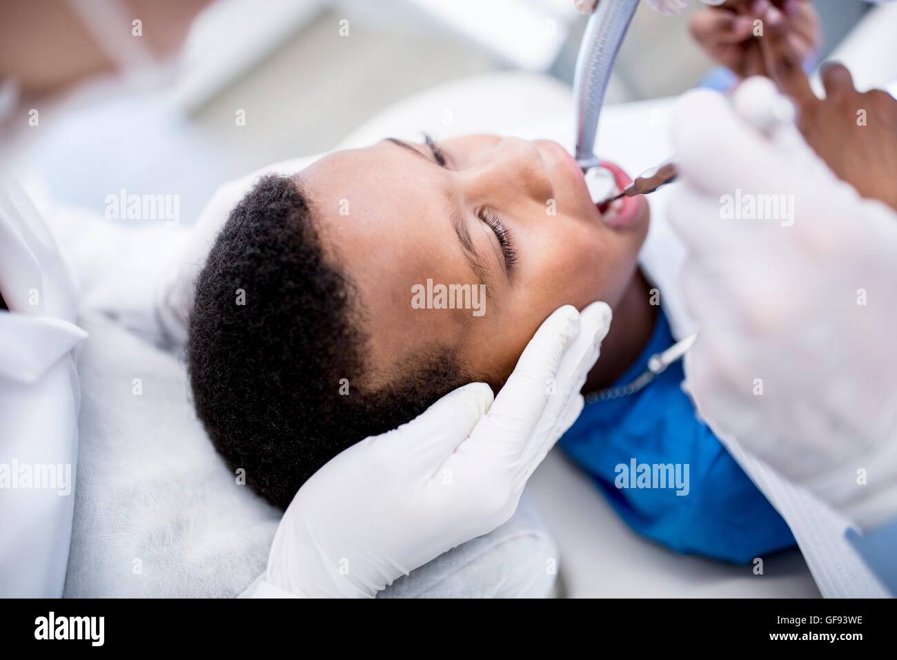 MODEL RELEASED. Dentist drilling boy's teeth in clinic. Stock Photo