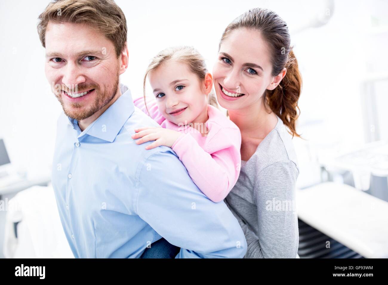 MODEL RELEASED. Portrait of dentist and dental assistant playing with girl in clinic, smiling. Stock Photo