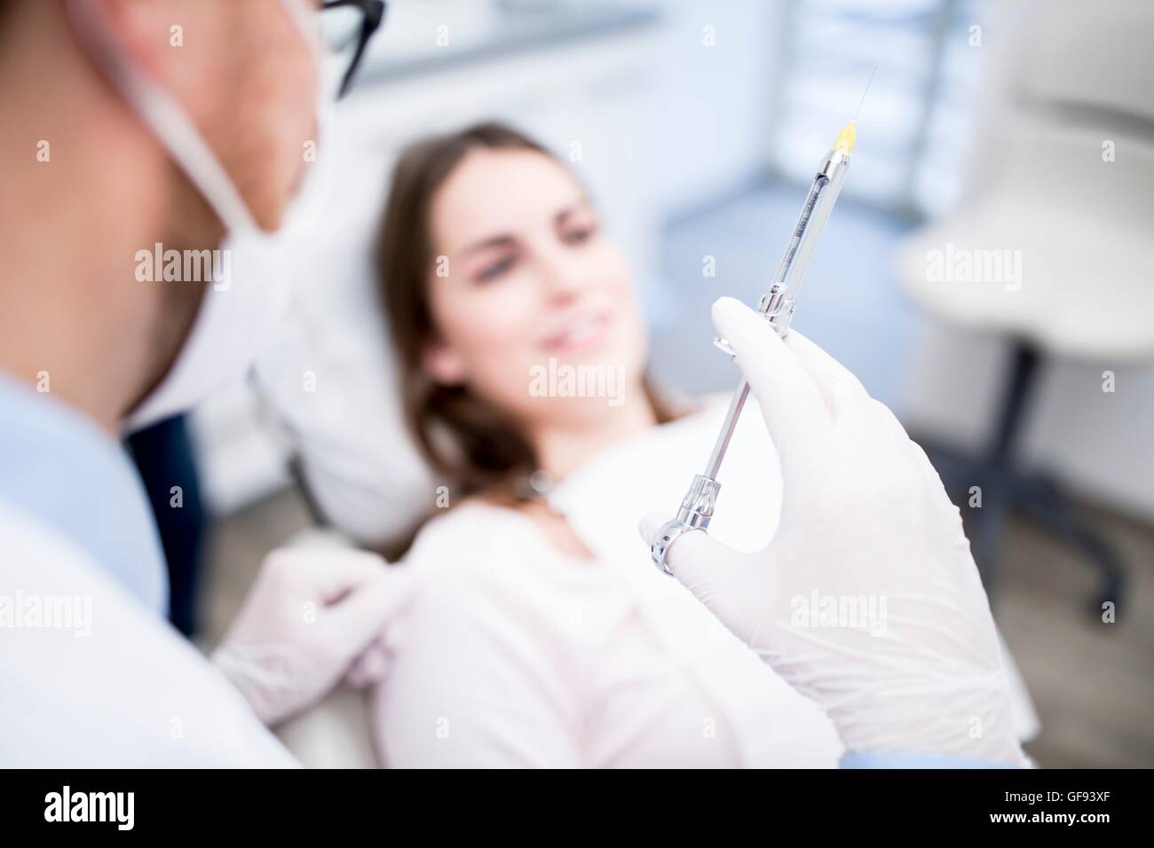 MODEL RELEASED. Dentist holding syringe in dentist clinic Stock Photo