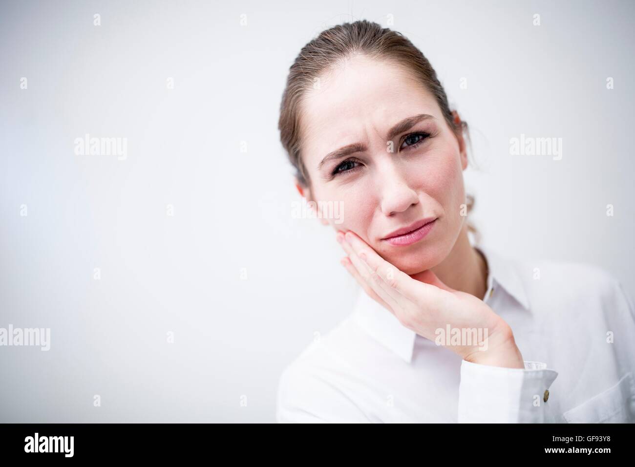 MODEL RELEASED. Young woman suffering from toothache, studio shot. Stock Photo