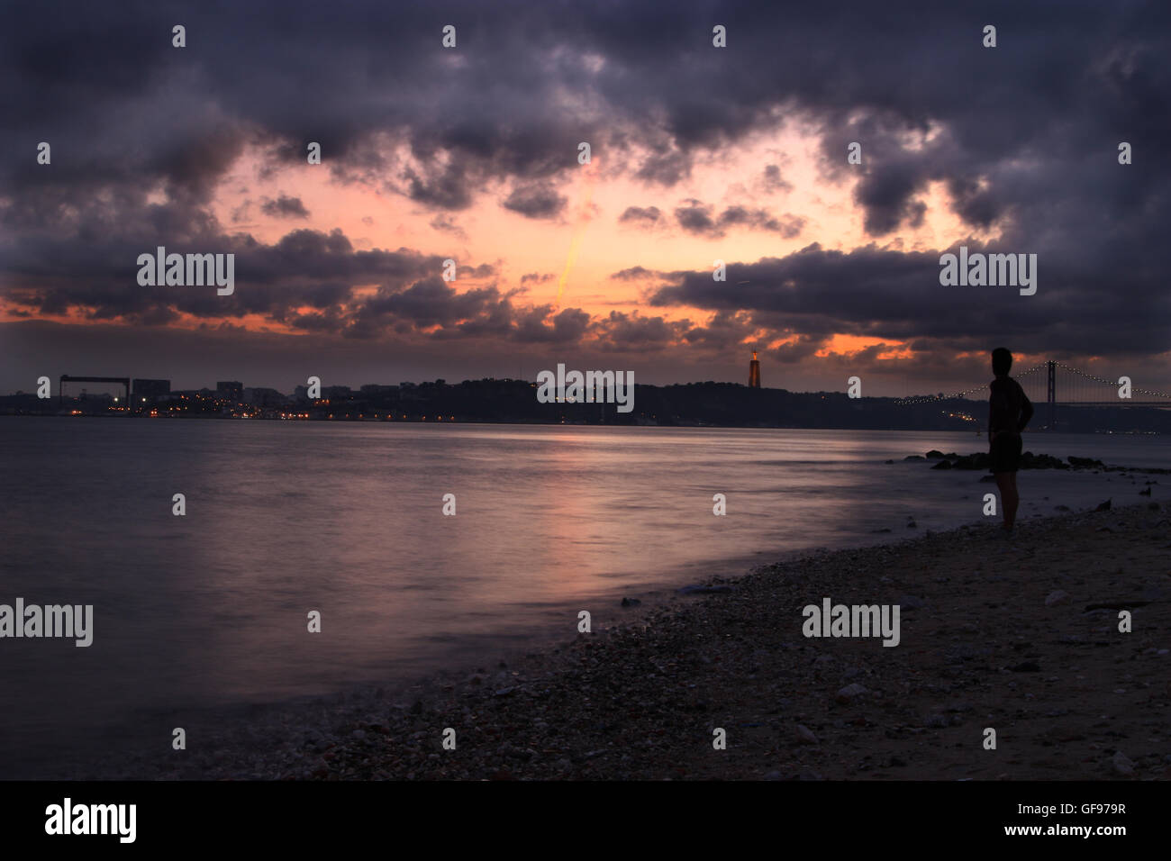 River view from the beach at sunset. City lights on other margin and bridge Stock Photo