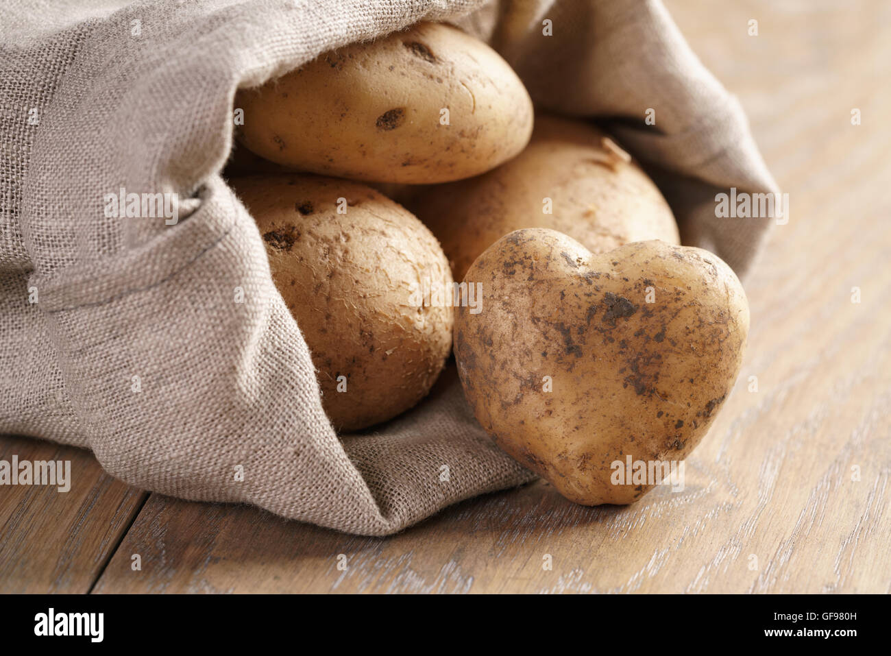 https://c8.alamy.com/comp/GF980H/sack-full-of-organic-potatoes-on-oak-wooden-table-GF980H.jpg