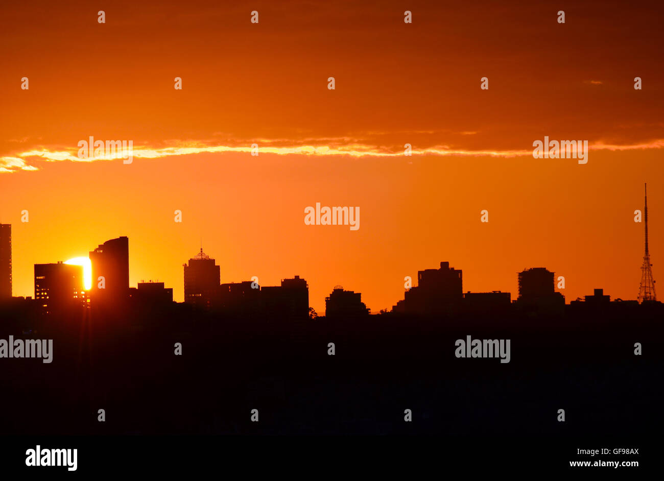 Glowing orange sun setting behind city buildings in silhouette (North ...