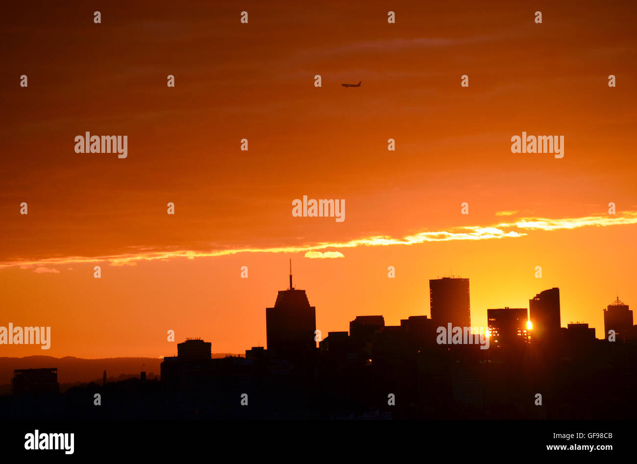 Glowing orange sun setting behind city buildings in silhouette (North ...