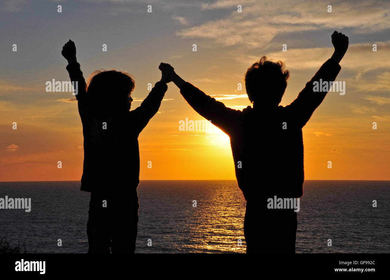 Two boys on sunset with the hands up Stock Photo