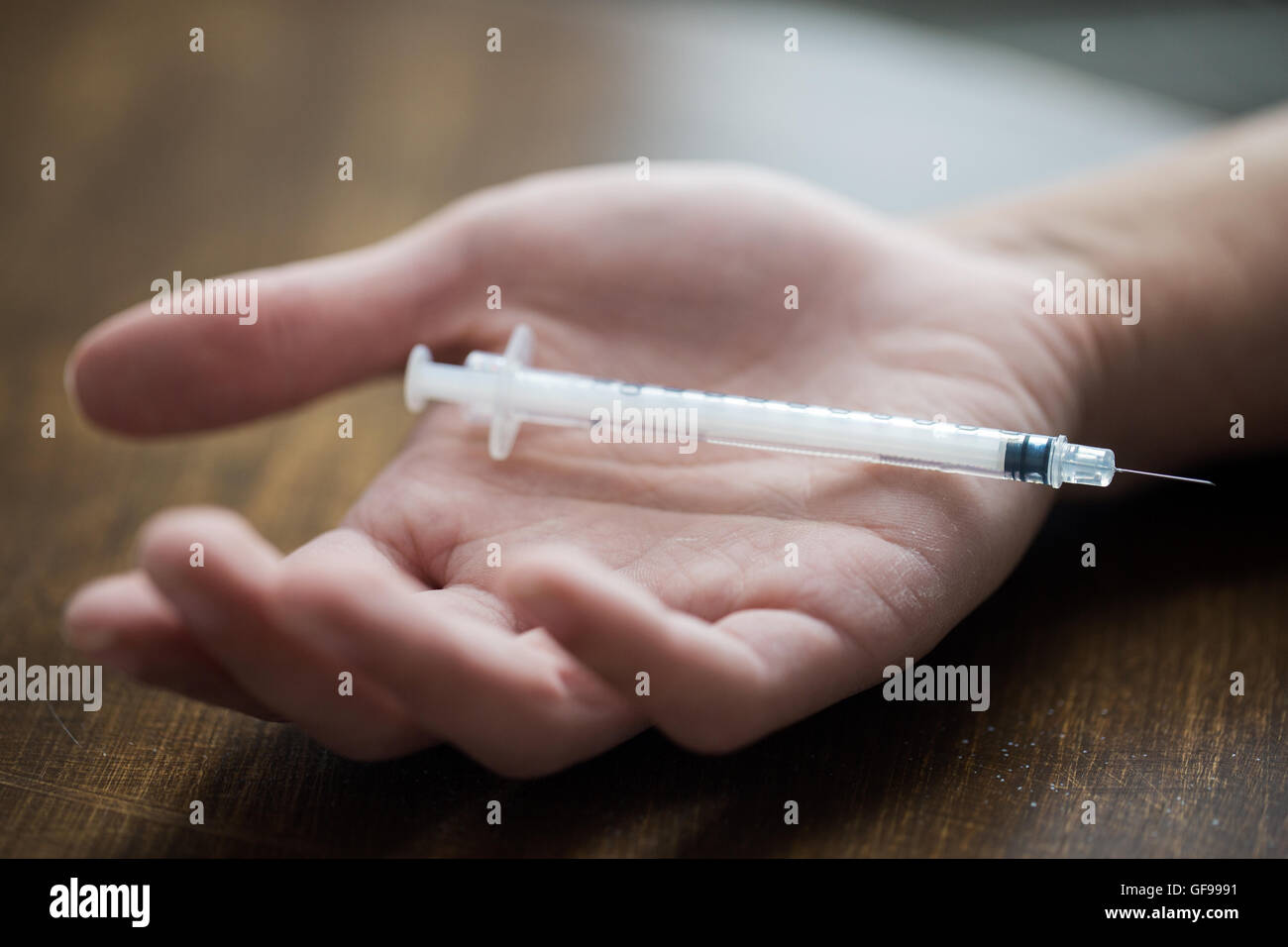 close up of addict hand and used drug syringe Stock Photo