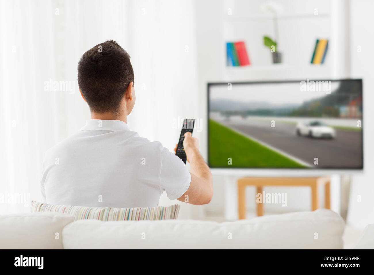 man with remote watching motorsports on tv at home Stock Photo
