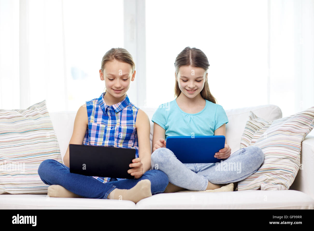 happy girls with tablet pc sitting on sofa at home Stock Photo - Alamy