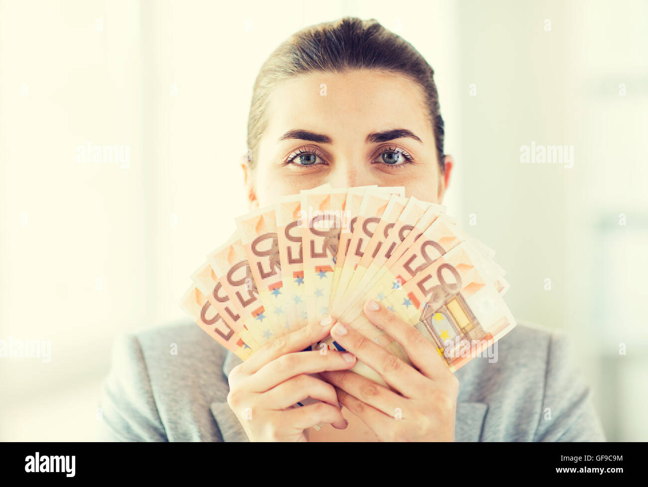 woman hiding her face behind euro money fan Stock Photo