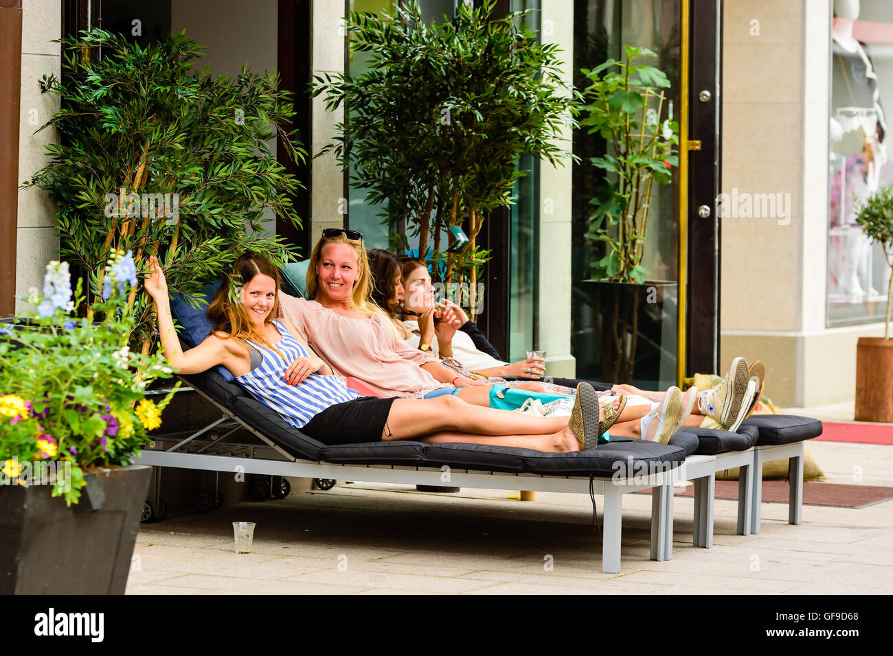 Goteborg, Sweden - July 25, 2016: Real people in everyday life. Four lovely young women lie down outside a coffee shop with smil Stock Photo