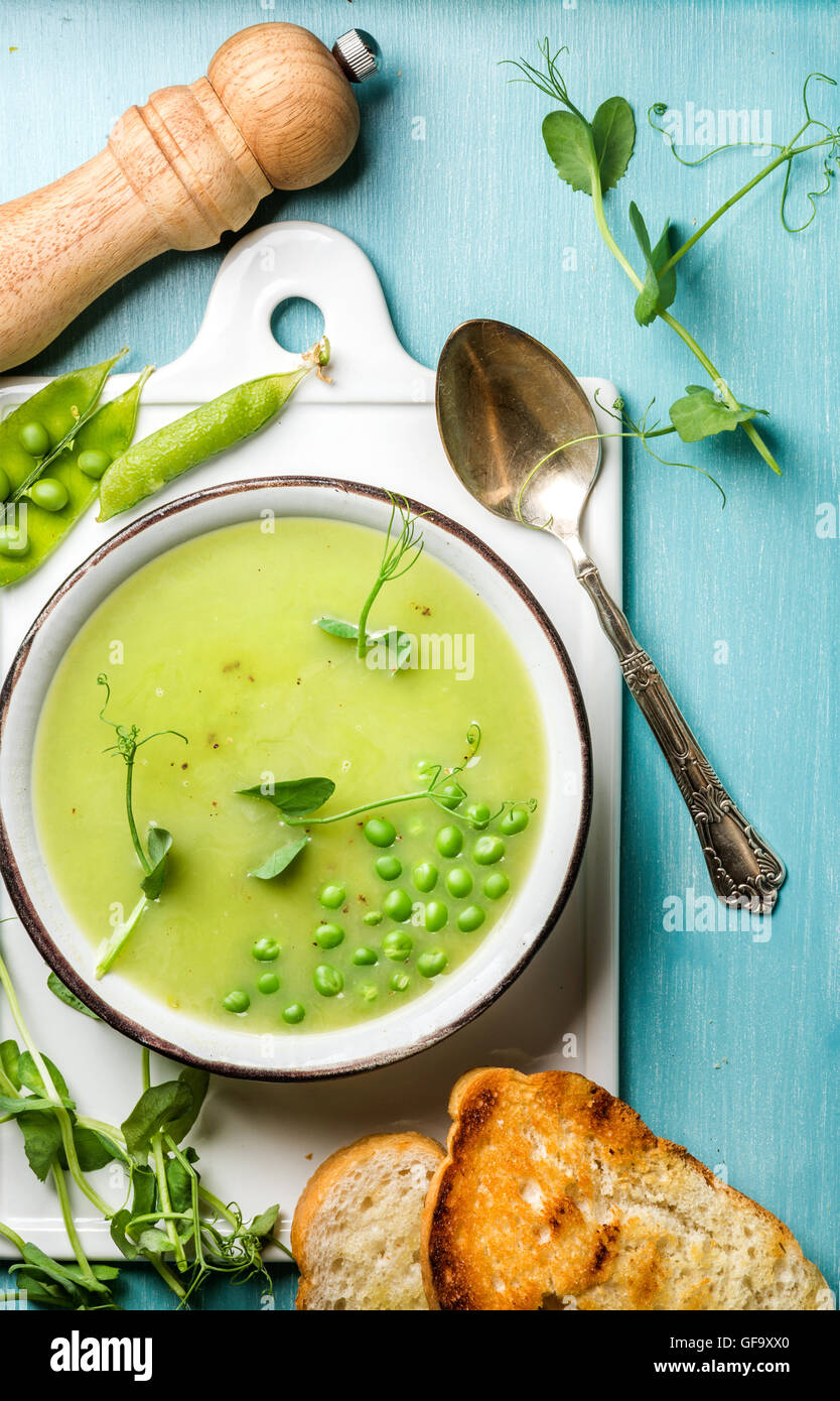 Light summer green pea cream soup in bowl with sprouts, bread toasts and spices Stock Photo