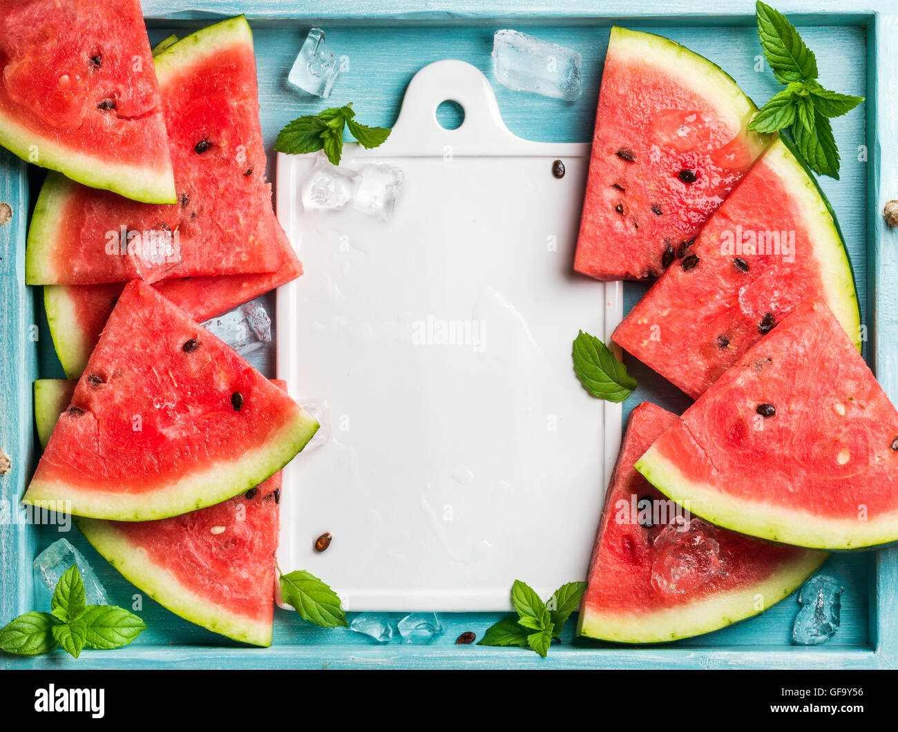 Watermelon slices with ice cubes and mint leaves on blue wooden ...